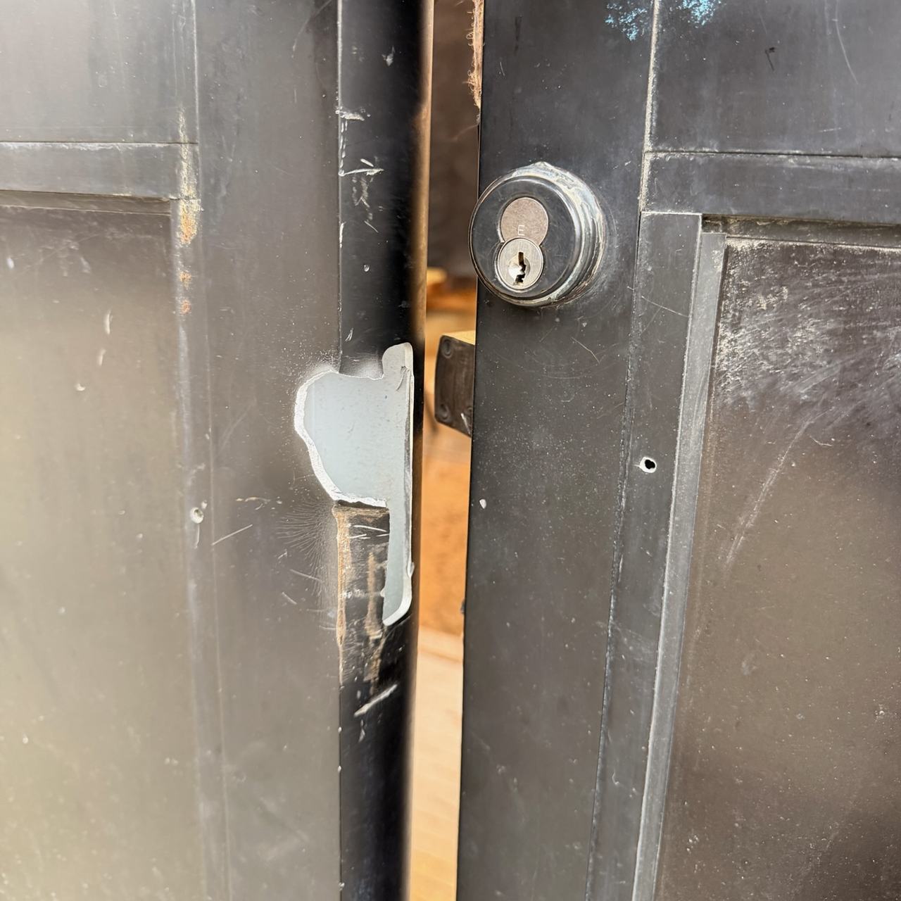 Damaged strike and frame area on a storefront entrance after break-in