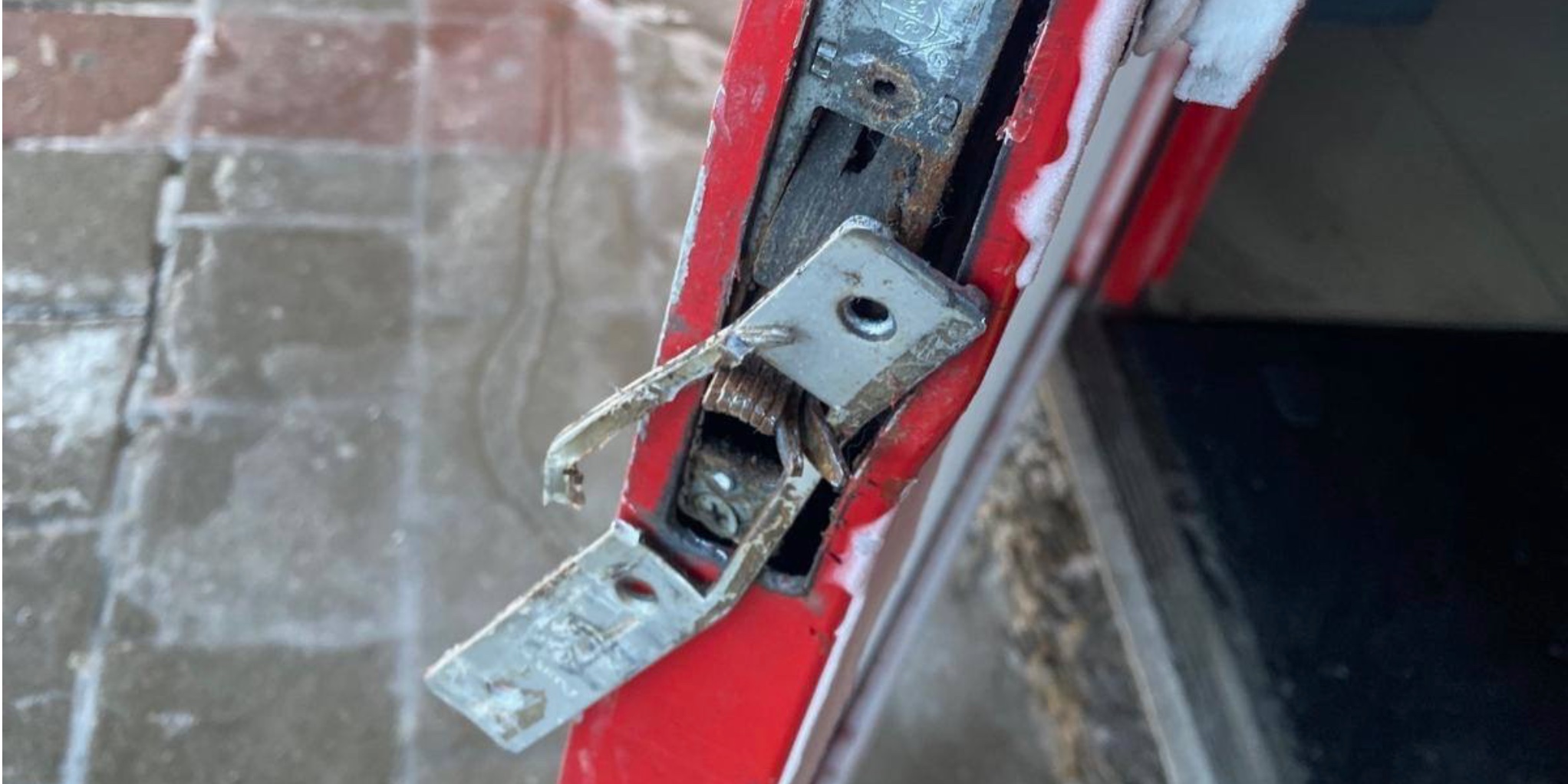 Forced-entry damage around the lock stile of a red commercial aluminum door
