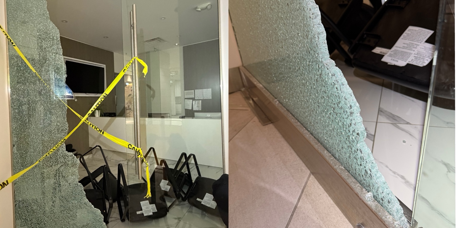 Shattered storefront glass cordoned off with caution tape before board-up