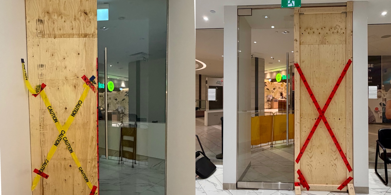 Plywood board-up installed over a damaged storefront glass panel