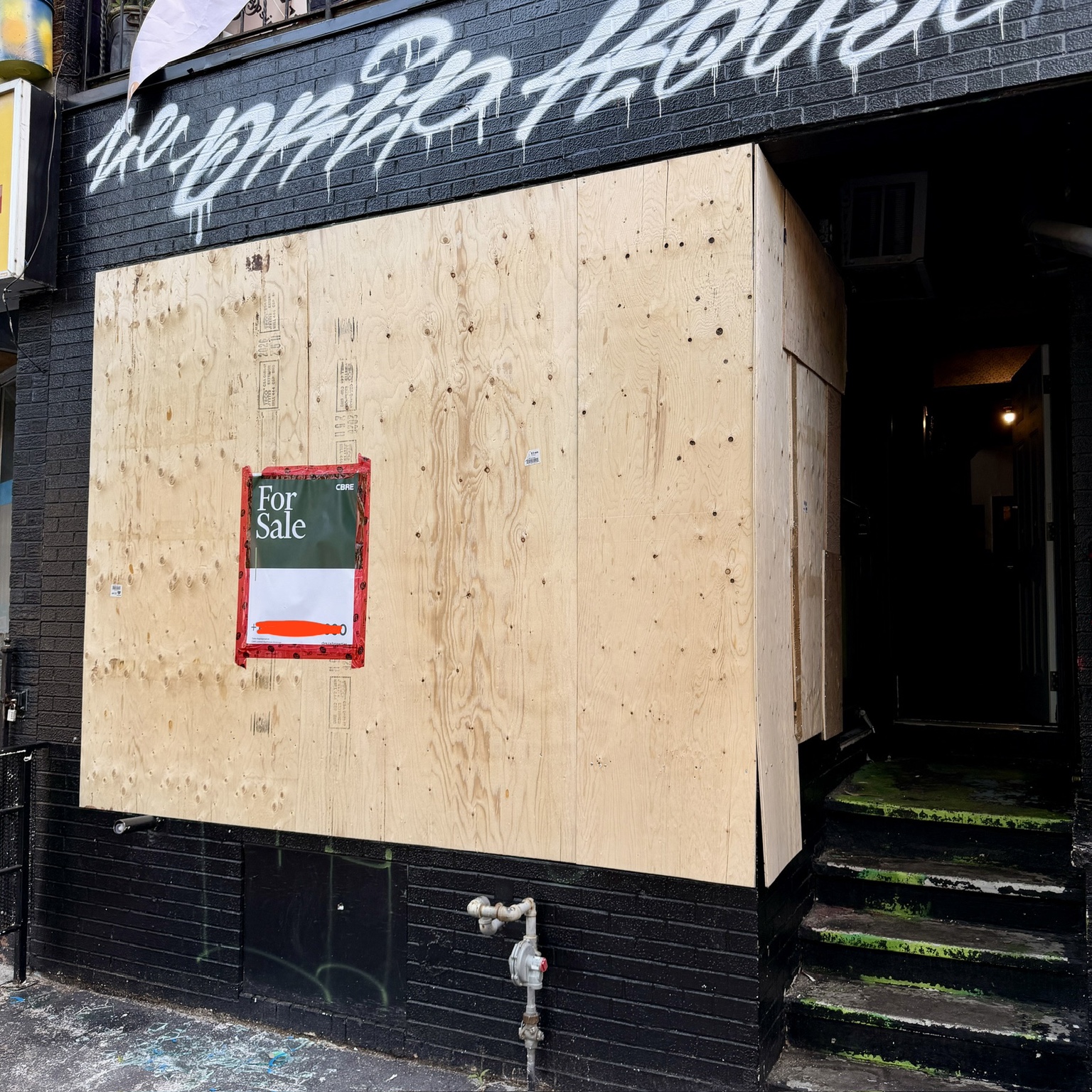 Large storefront opening secured with plywood board-up by DoorWin Services