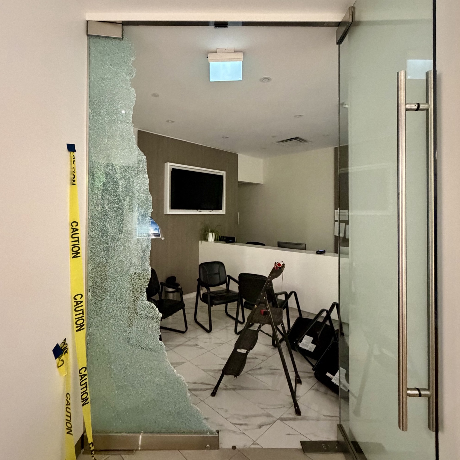 Shattered storefront glass beside a commercial glass entrance door