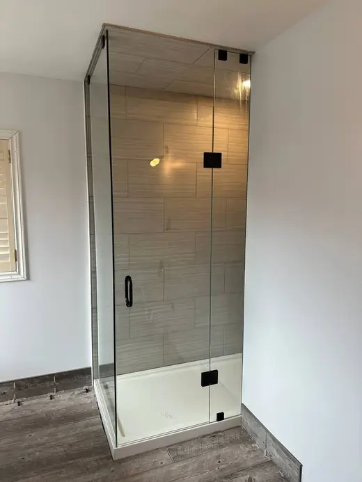 Custom frameless shower glass installed around finished tile and bench in Milton