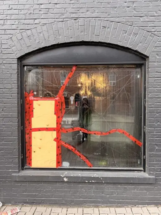 Damaged tattoo studio storefront opening in Parkdale before permanent glass replacement