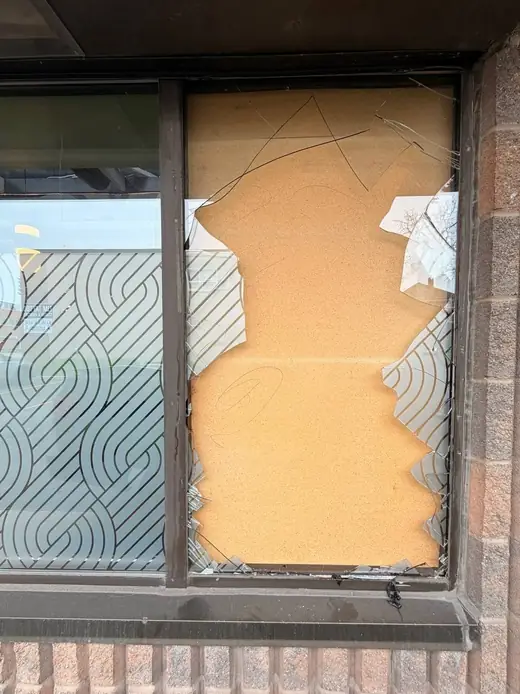 Boarded broken storefront window in Burlington before glass replacement