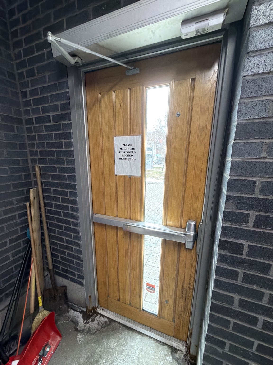 Interior view of old commercial door with panic bar and closer before replacement