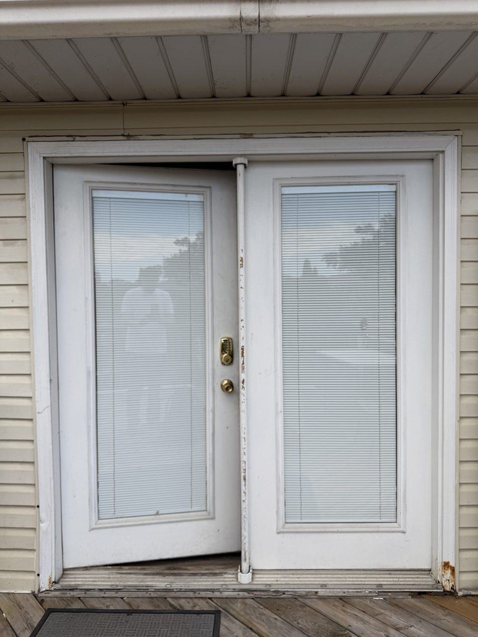Old white French patio doors before replacement with built-in blinds upgrade planned
