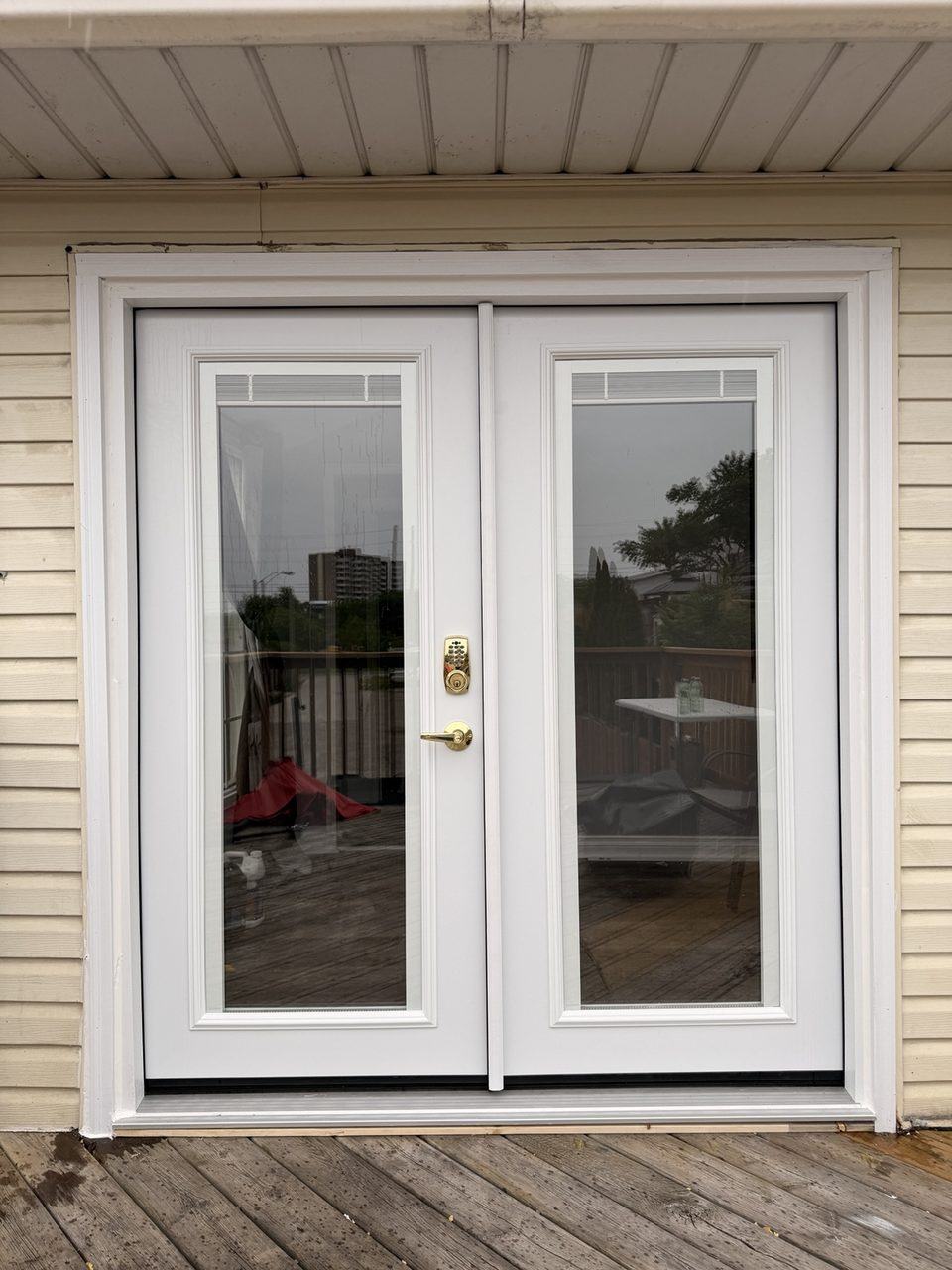 Finished exterior view of new white French patio doors with internal blinds installed