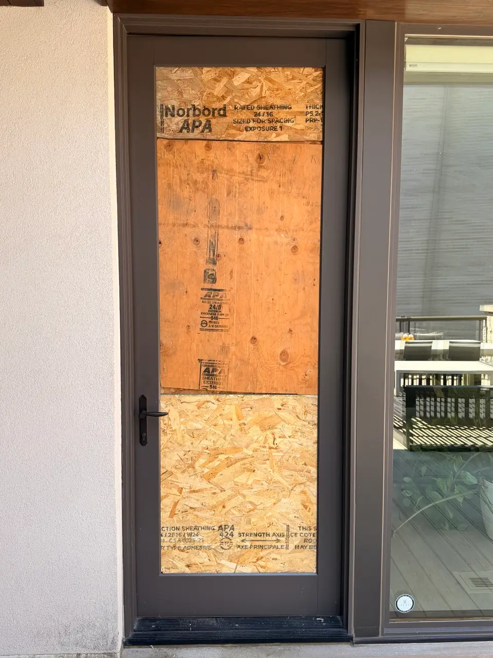 Custom plywood board-up securing broken balcony door glass in Georgina