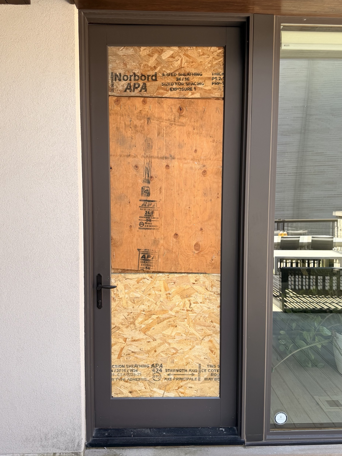 Custom plywood board-up securing broken balcony door glass in Georgina
