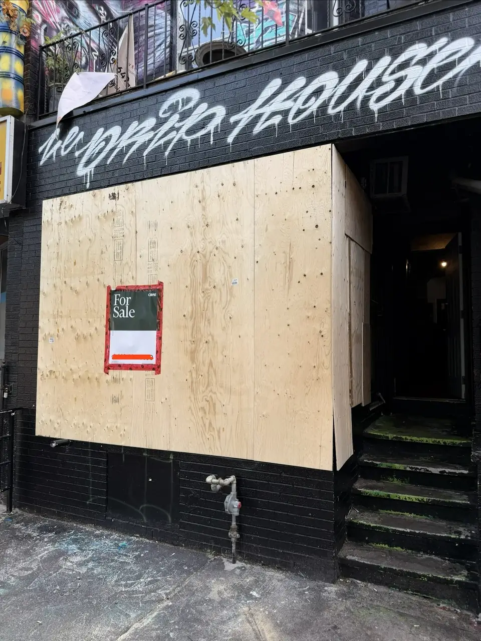 Emergency plywood board-up installed over a damaged storefront opening in Kensington Market, Toronto