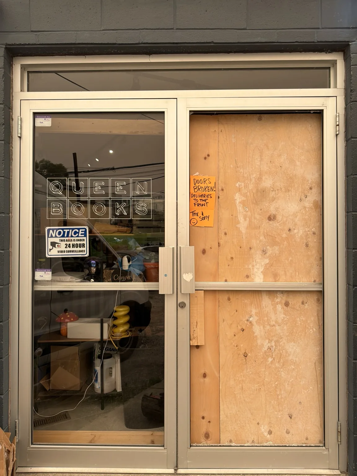 Boarded aluminum storefront door in Leslieville before same-day glass replacement